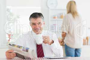 Man sitting at the kitchen table while holding a cup of coffee b