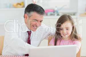 Man and girl sitting at the kitchen with laptop
