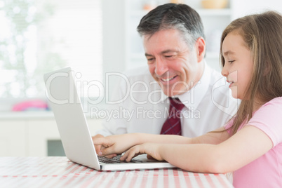 Girl typing with father watching