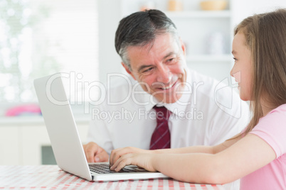 Man and daughter sitting at the kitchen at laptop