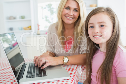 Woman typing at the laptop with daughter