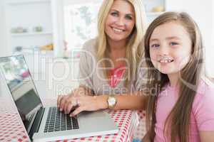 Woman typing at the laptop with daughter