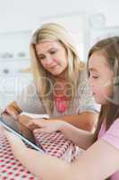 Mother and girl sitting while holding a tablet computer