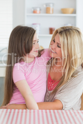 Mother and daughter looking lovingly at each other in kitchen