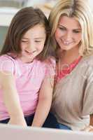 Mum and child sitting and smiling at laptop