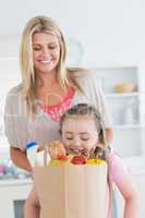 Daughter looking into grocery bag with mother watching