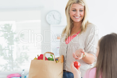 Mother passing tomato to child from grocery bag