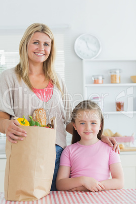 Woman and her little girl smiling at the kitchen