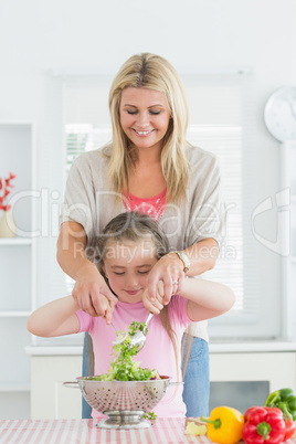 Woman and child mixing salad together