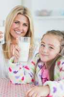 Mother and girl holding up glasses of milk