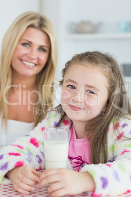 Little girl drinking a glass of milk with her mum
