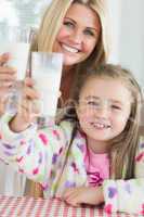 Mother and daughter raising milk glasses