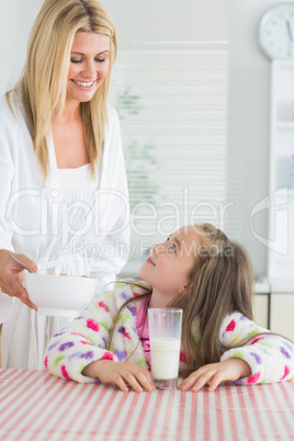 Mother giving cereal to little girl