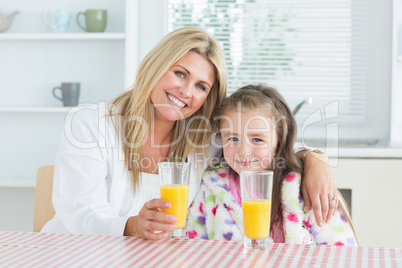 Woman and little girl sitting at the kitchen having juice