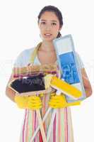Frowning woman holding brushes and mops