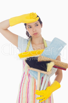Overworked woman holding cleaning tools