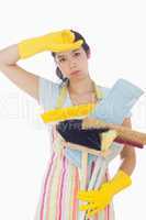 Tired woman holding cleaning tools