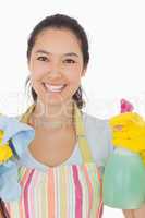 Happy woman holding spray bottle and rag