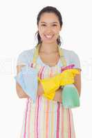 Woman standing with arms crossed holding cleaning products