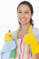Smiling woman with cleaning products giving thumbs up