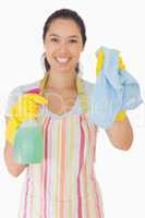 Smiling woman holding up rag and spray bottle