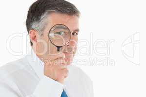 Businessman looking through magnifying glass