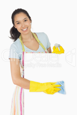 Cheerful woman wiping down white surface