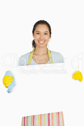 Woman in apron and rubber gloves holding white surface
