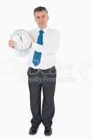 Serious businessman holding clock