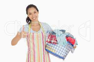 Woman carrying laundry basket and giving thumbs up