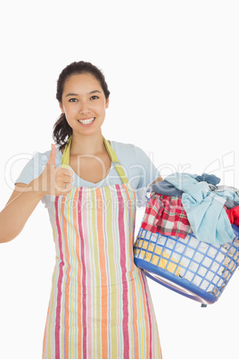 Laughing woman holding laundry basket full of dirty clothes
