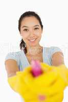 Smiling woman pointing spray bottle at the camera