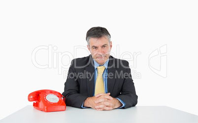 Calm man sitting at his desk with a phone