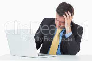 Troubled man sitting at his desk with a laptop