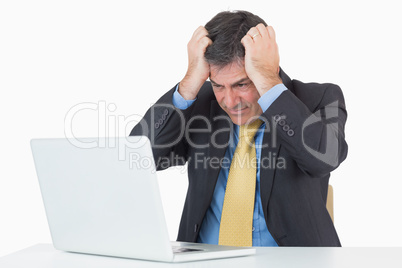 Anxious man sitting at his desk with a laptop