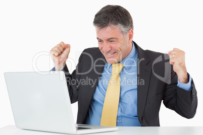 Very happy man sitting at his desk with laptop