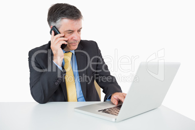 Man phoning while writing on laptop