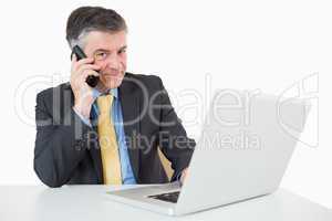 Happy man phoning while typing on laptop
