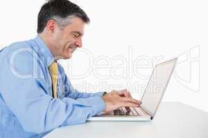 Man smiling while writing on his laptop