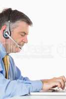 Businessman with headset writing on laptop