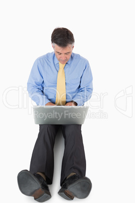 Businessman sitting on floor working on laptop