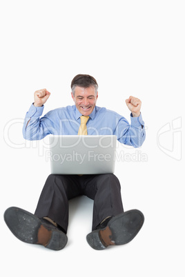 Cheering man with laptop on the floor