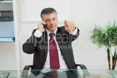 Businessman phoning and pointing