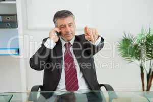 Businessman phoning and pointing