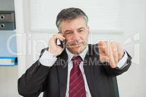 Businessman phoning and pointing