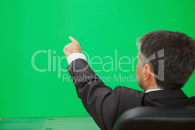 Businessman pointing on a green wall