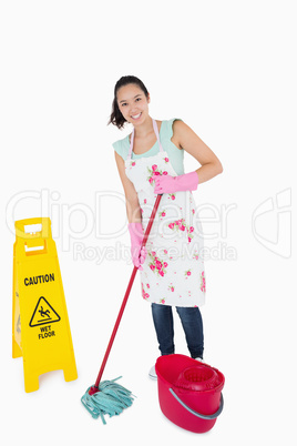 Woman cleaning near a caution sign