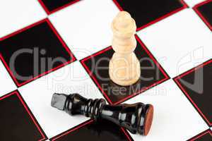 Black chess piece lying with white standing