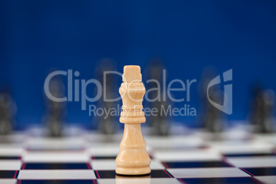 White queen standing at the chessboard while black ones standing