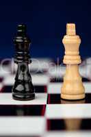 Black and white queen standing at the chessboard against blue ba